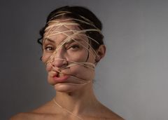 Kvinna har ansiktet inlindat med gummisnoddar.