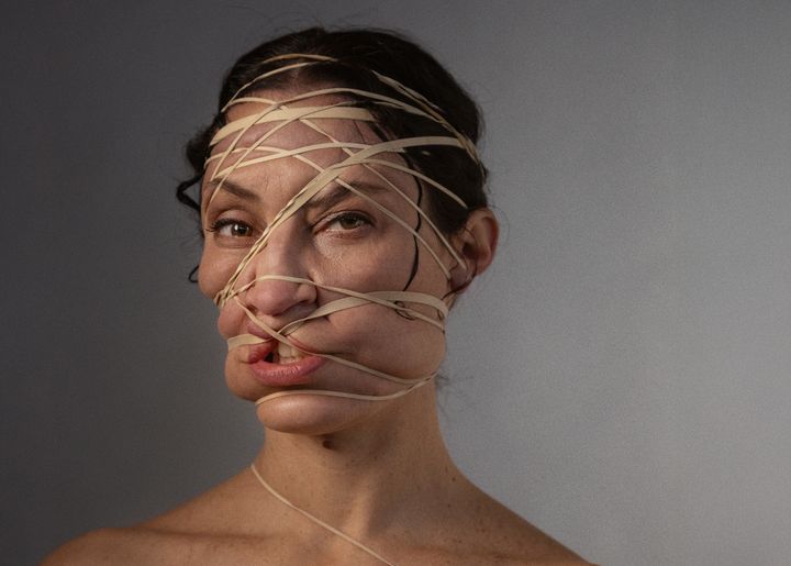 Kvinna har ansiktet inlindat med gummisnoddar.