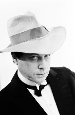 Helge Skoog i smoking och bredbrättad hatt ser in i kameran, porträtterad i svartvit närbild.