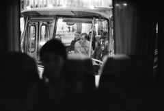 Svartvit bild av personer som går på en buss, sedd genom fönstret från insidan av en annan buss.