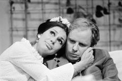 Gurie Nordwall i vit klänning lutar huvudet mot Helge Skoog i kavaj och håller hans kind.