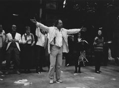 Helge Skoog med utsträckta armar står framför grupp vuxna i scenkläder.