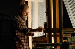 En man som väver vid en vävstol.