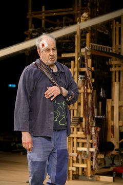 En man med en bandagerad panna, stående framför en komplex fond.