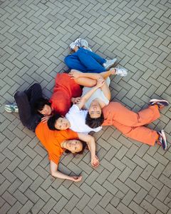 Fyra personer ligger på marken i en cirkel och håller i varandra.