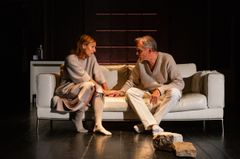 Två personer sitter på en soffa och håller varandras händer.