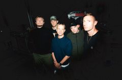 Fem personer står tillsammans i en mörk omgivning.