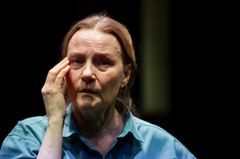 En person i en tankfull pose på en teaterscen.