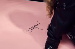 Person skriver ord på ett rosa papper.