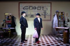 Andreas T Olsson och Claes Eriksson köandes i svarta kostymer. På väggen bakom står Godots diversehandel