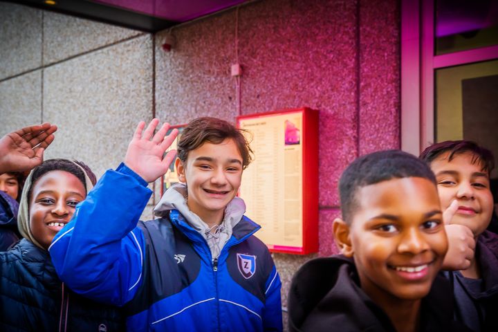 En grupp glada barn står utanför Kulturhuset Stadsteatern och vinkar.