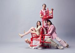 Kreativ gruppfotografering med fyra personer som poserar med röda stolar.