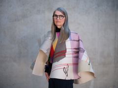 Anna Nyberg i långt grått hår iklädd en färgglad målarcanvas som en poncho.