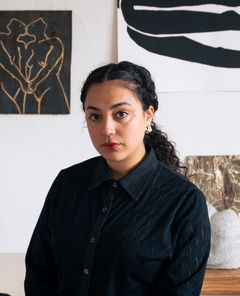 Porträtt av Yasmina Karli Malmsten i mörk skjorta och uppsatt hår.