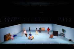 Ensemblen på scenen för "Bön för idioter", omgiven av rekvisita som piano, stege och fåtölj.