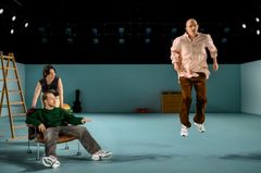 Three actors performing on stage in a modern theater setting.