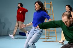 Fyra personer agerar energiskt på en scen med en stege i bakgrunden.