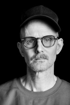 Porträtt av David Wiberg med glasögon och keps.