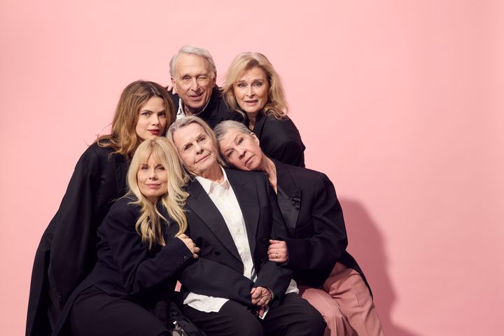 Gruppbild på sex personer framför en rosa bakgrund. De är klädda i mörka kläder och ser in i kameran.