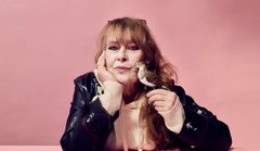 Kvinna i läderjacka lutar ansiktet mot handen och håller en liten fågel.