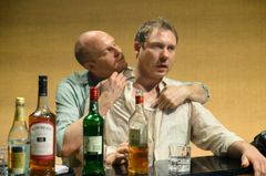 Två bröder som pratar vid ett bord med sprit