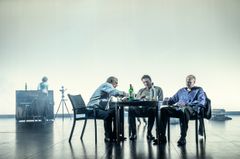 Tre skådespelare vid ett bord med alkohol på.