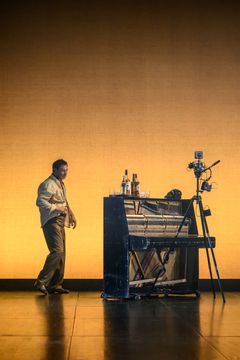 Ett piano och en skådespelare i bakgrunden.