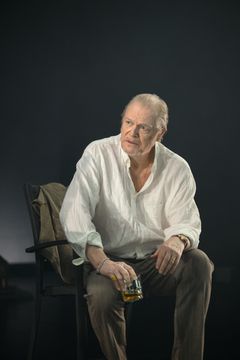 Skådespelaren Peter Andersson i en stol med ett glas i handen.