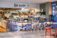 Barområde på en restaurang med blå stolar och inredning, skylt med texten "Blå baren".