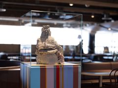 Keramisk skulptur av Valeria Montti Colque i en glasmonter, placerad på en färgglad piedestal.
