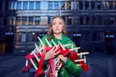 Skådespelaren Astrid Drettner med ljusstakar i händerna framför ett kontorshus.