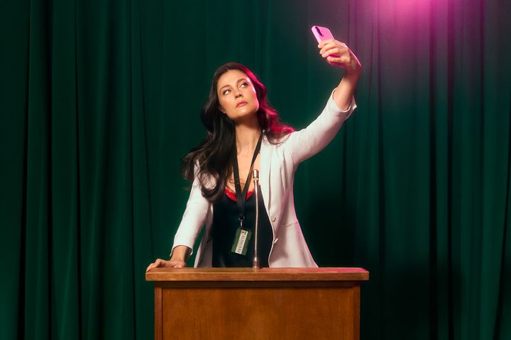 Person i talarstol som håller upp en telefon för att ta bild.