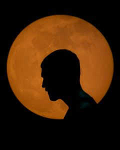 Silhuett av en person mot en stor, orange bakgrund.