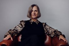 Susanna Alakoski sitter i en fåtölj med händerna på armstöden.