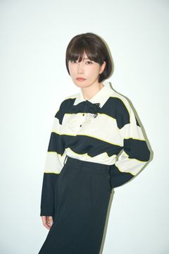 Mieko Kawakami i randig tröja och mörk kjol står mot en ljus bakgrund.