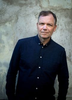 Arne Lygre står framför en vägg och bär en mörk skjorta.