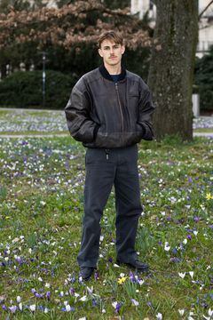 Nelio Biedermann står utomhus på en gräsmatta med blommor.