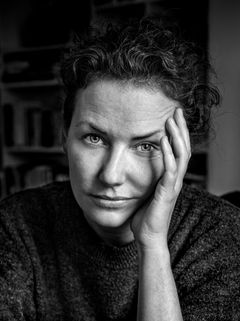 Svartvitt foto av en person med lockigt hår som lutar sitt ansikte mot handen