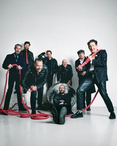 Gruppbild av flera personer i läderkläder med röda rep.