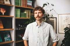 Aron Landahl i ett rum framför en bokhylla.
