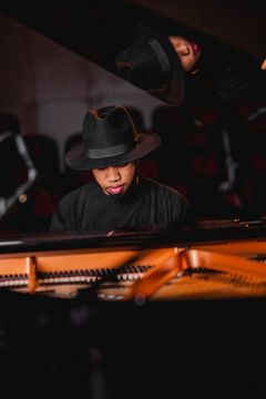 En musiker spelar piano med en svart hatt.