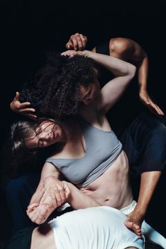 Dansare i en sammanflätad pose på scenen.