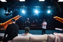 Ensemblen repeterar på scenen med Akse Pettersson som regissör. Bakgrundsbelysning lyser upp repetitionen.