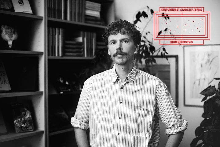 Svartvitt porträtt av Aron Landahl med mustasch och randig skjorta framför bokhyllor. Uppe till höger syns logotypen för Kulturhuset Stadsteaterns Bilderbokspris.
