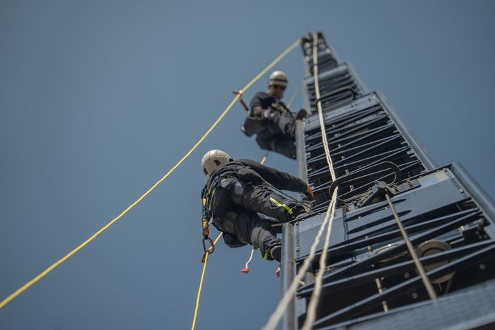 Serviceingenjörer som klättrar i mast