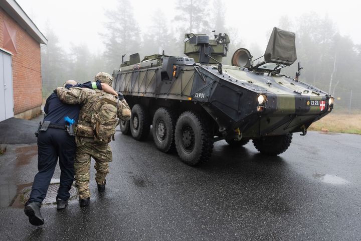 Två människor i uniform vid en stridsvagn