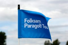 Blå golfflagga med logotypen Folksam Paragolf Tour vajar i vinden.