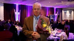 En person i kostym håller en blombukett på en middagsbankett.