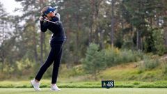 En golfspelare svingar en klubba på en golfbana.