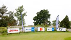 Skyltar och flaggor från sponsorer vid en golfbana, inklusive Destination Uppsala, ANNIKA foundation, Mastercard och R&A.